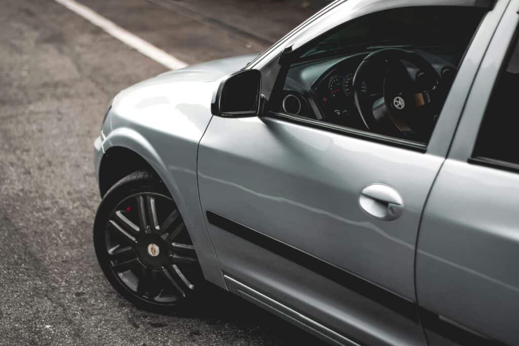 A detailed view of a silver car's side and interior in an urban environment, showcasing modern design.